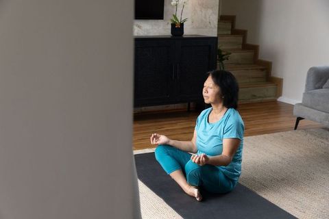 Serene Moment: Asian Woman Meditating on Yoga Mat at Home