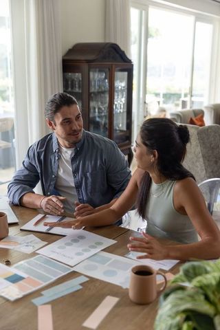 Couple reviewing home color palette and moodboard at dining table with notebooks and coffee