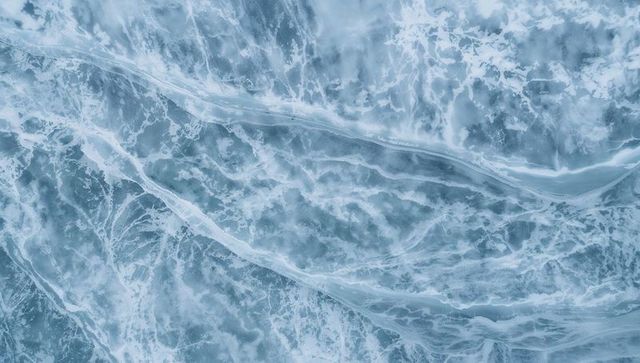 Churning ocean surface forming swirling foam and whitecaps across diagonal foam channel