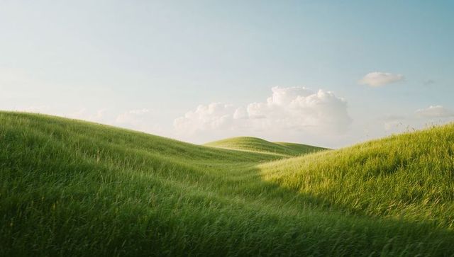 Rolling green hills blanketing sunlit meadow with soft clouds and breeze-swept grasses