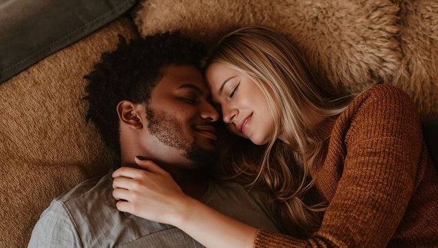 Couple cuddling on plush sofa with fuzzy throw in cozy knit sweater