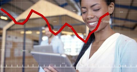 Smiling professional holding tablet with digital growth graph overlay in open-plan office