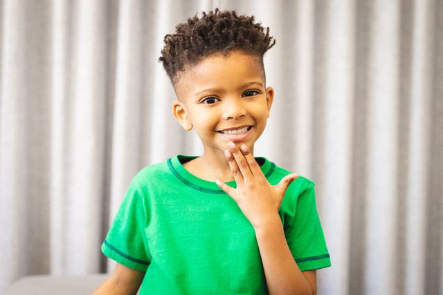 Happy african american boy talking in sign language. Hearing disorder, domestic life and childhood concept.