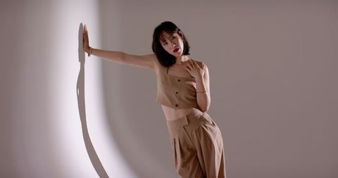 Elegant asian woman posing in studio with beige fashion