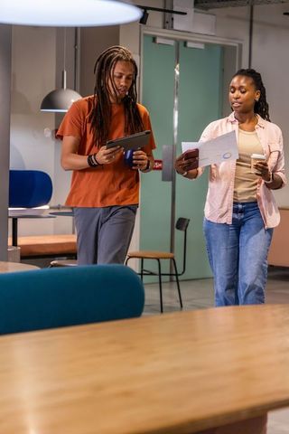African american coworkers walking through modern coworking lounge with tablet and coffee