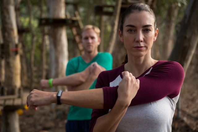 Woman stretching her arms with a trainer in a forest. Ideal for promoting outdoor fitness, healthy lifestyle, and nature workouts. Suitable for fitness blogs, wellness websites, and exercise programs.