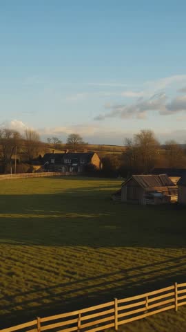 Tilting Vertical Video Revealing Sunlit Pasture, Fence, Rustic Farmhouse at Golden Hour
