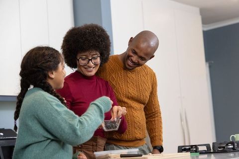 Cozy family baking cookies together on kitchen island, parents teaching child baking skills