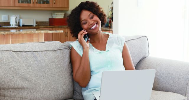 Happy woman talking on phone while using laptop at home - Download Free Stock Images Pikwizard.com