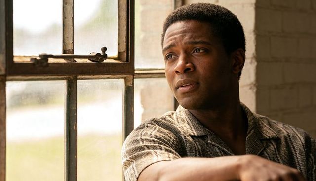 Pensive black man gazing out industrial window, leaning on windowsill, contemplative mood