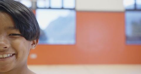 Joyful boy smiling in bright orange room with windows