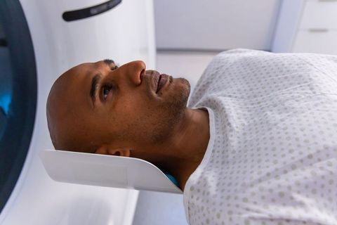 African american man undergoing mri head scan in hospital radiology, patient lying calm