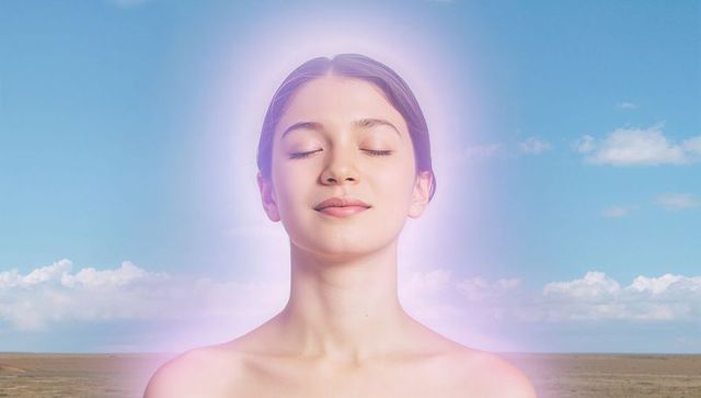 Meditating woman with pink-purple aura in open grassland horizon, serene spiritual energy