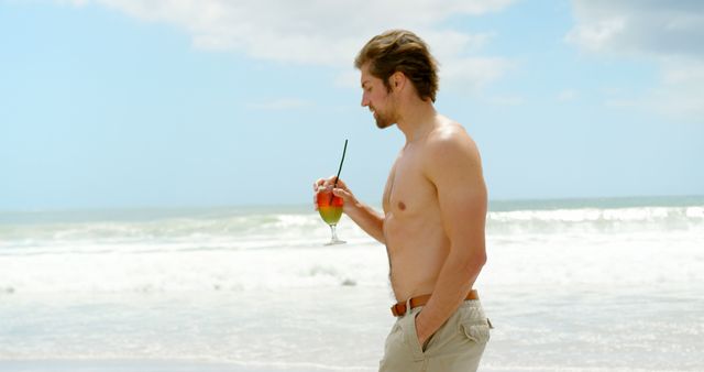Young Man Enjoying a Tropical Drink on Ocean Beach - Download Free Stock Images Pikwizard.com