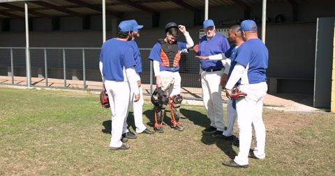 Baseball Team with Coach in Strategic Discussion at Dugout