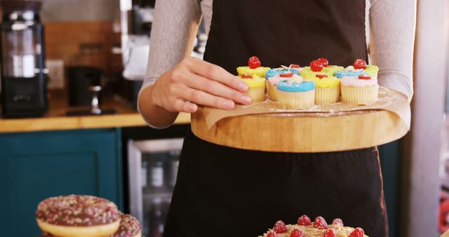 Baker Presenting Colorful Cupcakes in Cozy Bakery - Download Free Stock Images Pikwizard.com