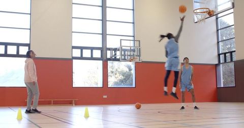 Team basketball practice with coach guiding shooting technique