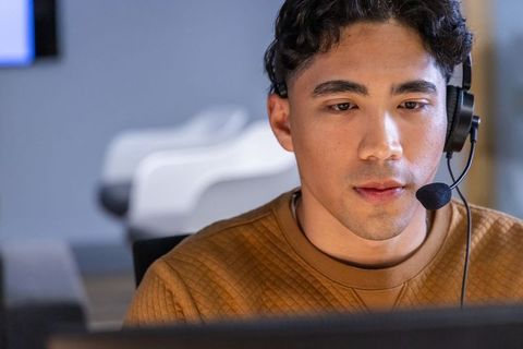 Young asian customer support specialist wearing headset working at modern office desk focused