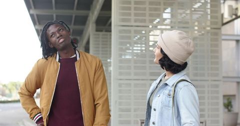 Diverse friends chatting on urban transit platform wearing casual bomber jacket and denim