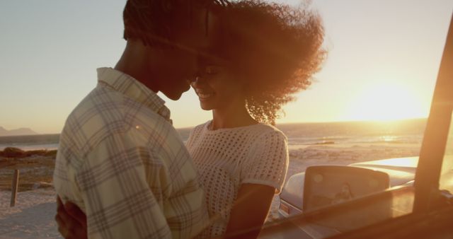 This image shows a romantic couple embracing near a beach during sunset. The lighting captures a warm and intimate moment, making it perfect for articles, advertisements, and social media posts focused on love, travel, and summer getaways.
