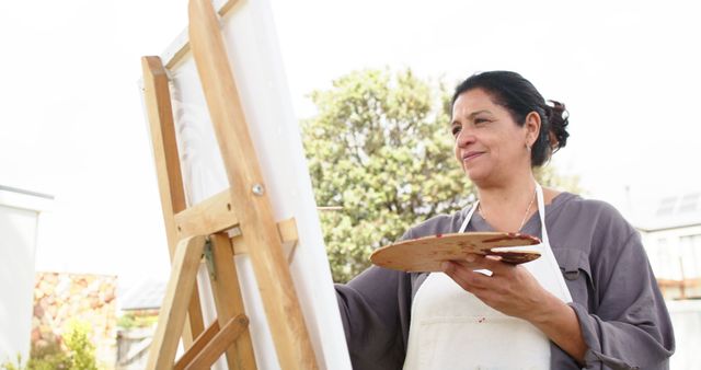 Middle-aged female artist painting outdoors on sunny day - Download Free Stock Images Pikwizard.com