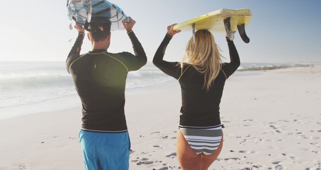 Diverse couple holding surfboards and walking on beach. Lifestyle, realxation, nature, free time and vacation.