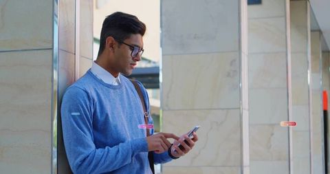 Man in blue sweater using smartphone on urban transit platform