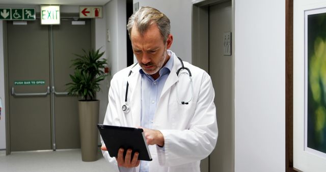 Doctor Reviewing Patient File on Tablet in Hospital Corridor - Download Free Stock Images Pikwizard.com