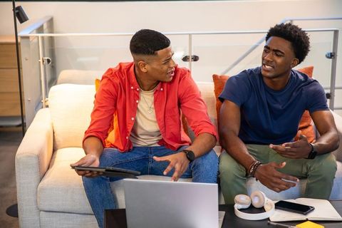 Young Male Friends Collaborating on Tech Devices in Modern Living Room