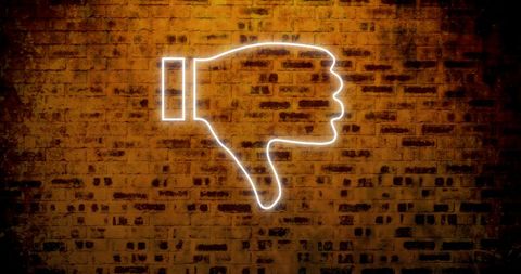 Thumbs down icon glowing on dark brick wall