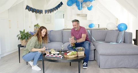 Mature Couple Celebrating Birthday with Cake and Champagne at Home