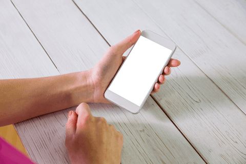 Hand holding smartphone with transparent edges on wooden table