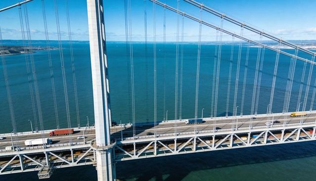 Aerial Suspension Bridge Tower Carrying Trucks on Steel Truss Roadway Over Blue Bay
