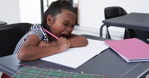 Young Girl Yawning and Studying in Classroom Setting