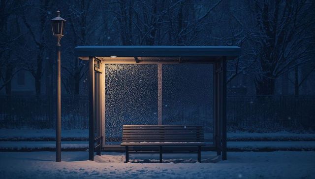 Snowy bus shelter glowing warm light on frosted glass bench under lamppost at night