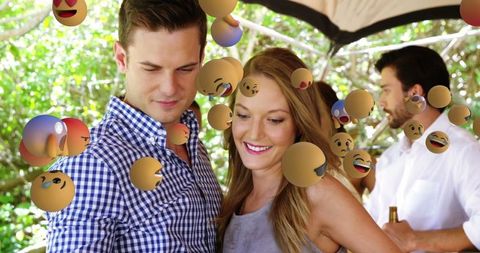 Couple Celebrating with Floating Emojis at Outdoor Party