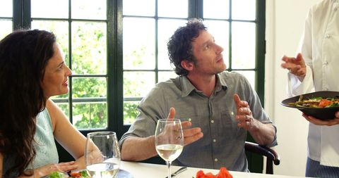 Couple Conversing with Chef in Elegant Restaurant Setting