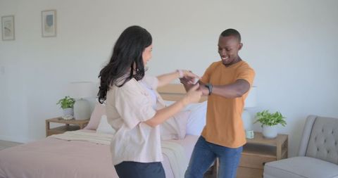 Hispanic woman and partner dancing in bright minimalist bedroom, romantic moment
