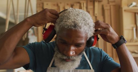African American Craftsman Adjusting Safety Ear-muffs in Workshop