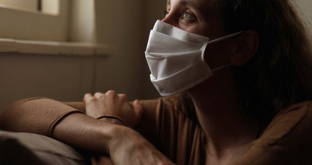 Pensive Woman Wearing Mask Sitting by Window - Download Free Stock Images Pikwizard.com