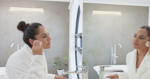 Asian Woman Engaged in Skincare Routine in Minimalist Bathroom