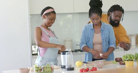 African american family preparing healthy meal together on modern kitchen island