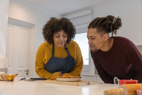 African american couple leaning over countertop inspecting homemade pie in cozy kitchen
