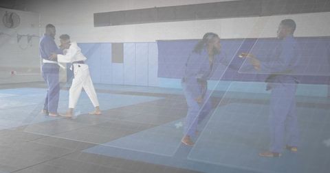 Practicing jiu-jitsu grappling drills with gis and belts on mats in training gym