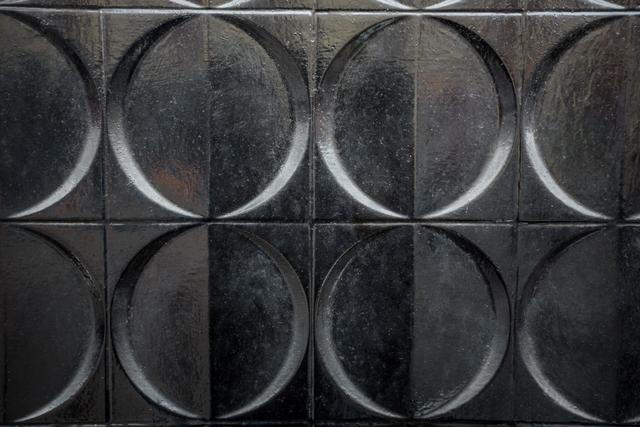 This image features a geometric circular pattern on a metal surface, creating a modern and industrial look. The symmetrical design and dark metallic texture make it ideal for use in backgrounds, wallpapers, and design projects that require a sleek and contemporary aesthetic.