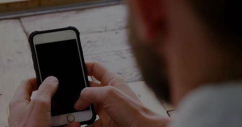 Mid Adult Man Using Smartphone Above Wooden Table for Communication