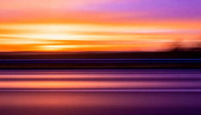 Glowing horizontal sunset bands mirroring across lake water, abstract streaked horizon