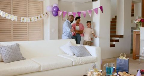 African American Family Celebrating Birthday Surprise in Living Room with Purple Decor