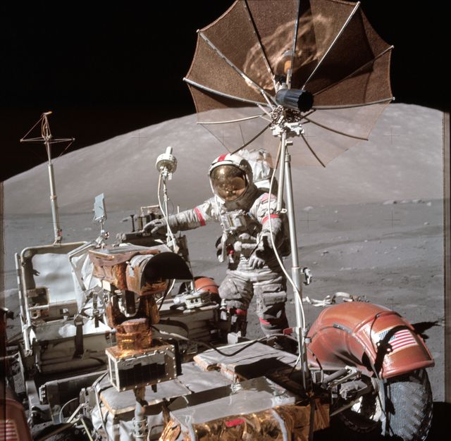 Astrocture Eugene A. Cernan is exploring the lunar surface near a parked Lunar Roving Vehicle (LRV) during the Apollo 17 mission in 1972. Captured by astronaut Harrison H. Schmitt with a Hasselblad camera, this photograph can be used in educational materials about space, advertisements for space-related products, or as historical documentation highlighting milestones in space exploration.