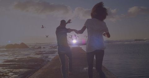 Couple Running Together on Coastal Rocks at Sunset